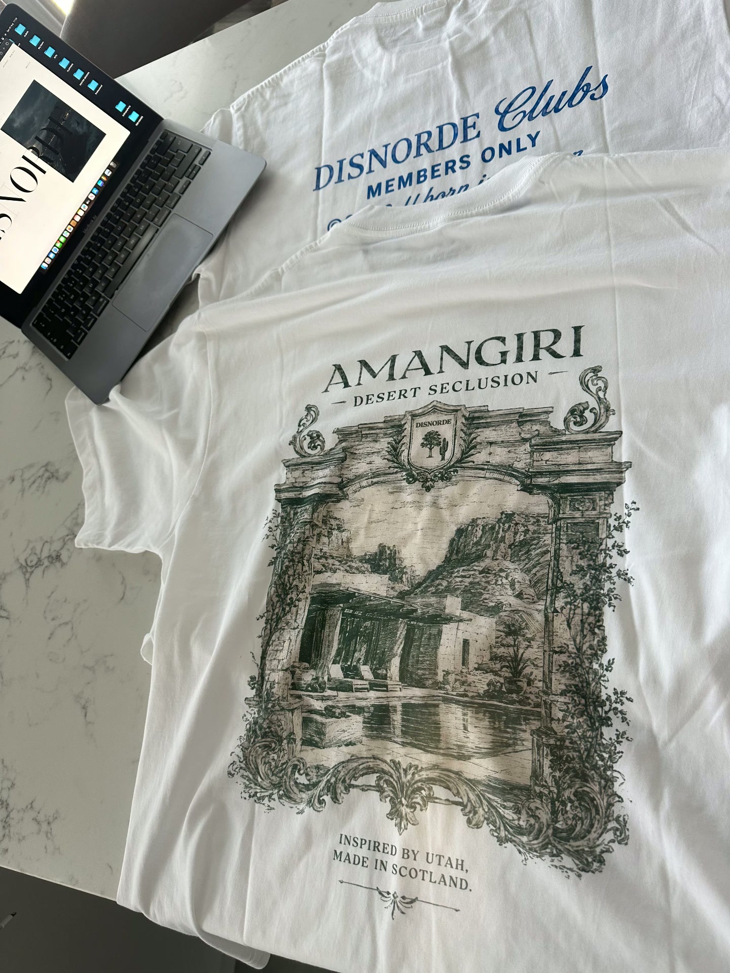 The Amangiri Desert Seclusion t-shirt laid flat, showing the architectural illustration and DISNORDE Clubs members-only detail